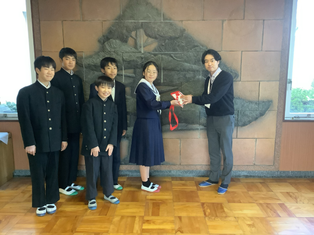 生徒会執行部から赤い羽根共同募金の役員の方に集まった募金を引き渡す様子